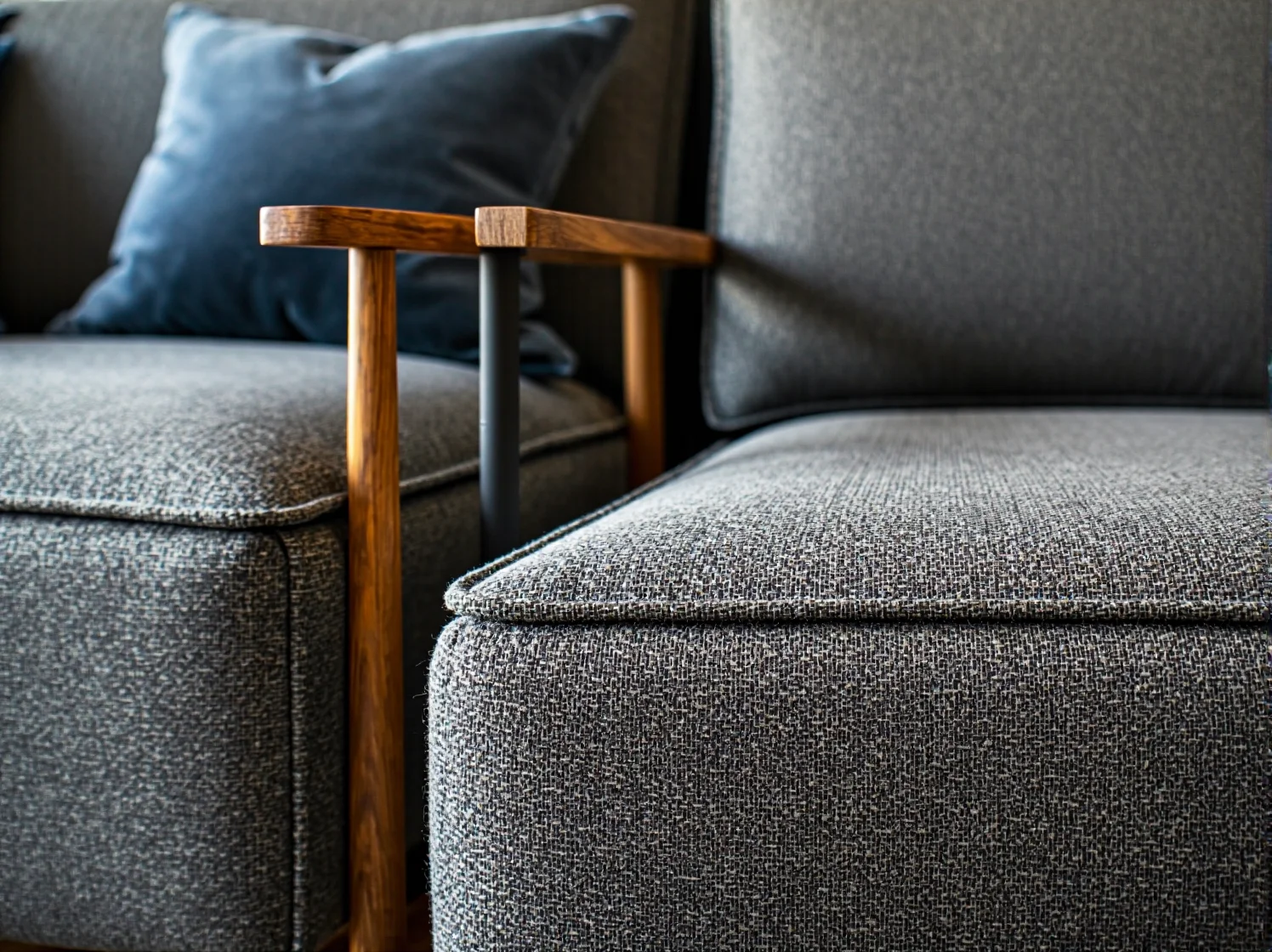 Szary fotel tapicerowany z drewnianym podłokietnikiem w stylu japandi